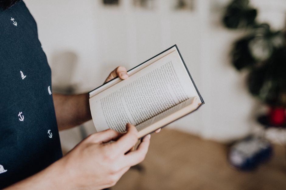 детские руки держат книгу с плотными страницами, ощупывая фактуру бумаги и переплета