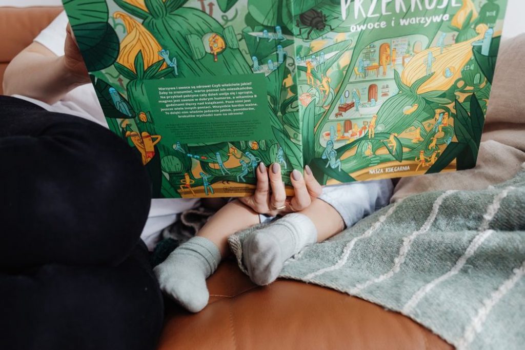 Малыш листает картонную книгу рядом с мамой