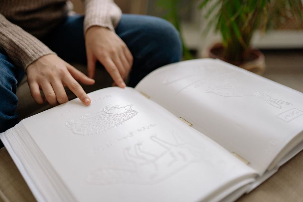 руки ребёнка держат раскрытую книгу дома